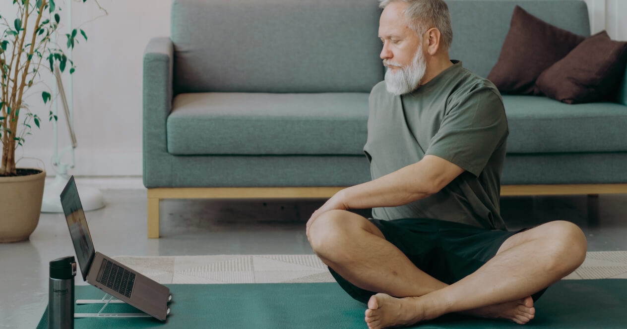 Man doing physical therapy exercise in front of his laptop