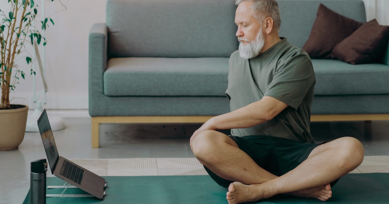 Man doing physical therapy exercise in front of his laptop